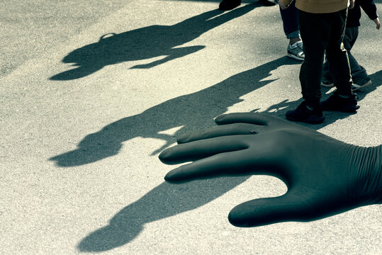 Shadows of a child on the street and a human hand in a black glove, conceptual picture of pedophilia and pedophile