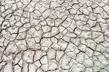 View from above onto surface of dried lake. Layer of mud cracked into endless count of pieces under the heat of the sun