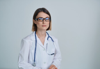 Professional woman doctor in a medical gown and glasses with a stethoscope around her neck