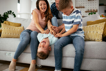 Young family enjoying at home. Mother and father tickling son.