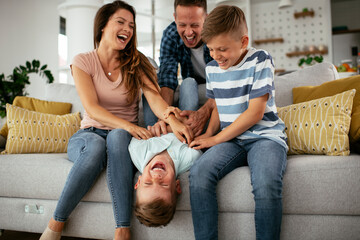 Young family enjoying at home. Mother and father tickling son.