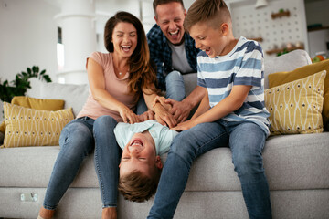 Young family enjoying at home. Mother and father tickling son.