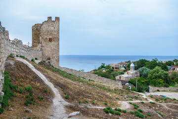 Fototapeta na wymiar Inside of Genoese fortress in Feodosia, Crimea. Medieval walls & tower are on foreground. Church of St. John The Baptist & Black Sea are on background