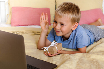 Cute boy congratulates via video link and gives a gift.