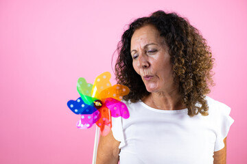 Middle age woman wearing casual white shirt standing over isolated pink background holding a...