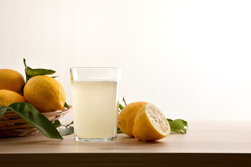 Glass with water with lemon on wooden table white background