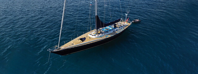 Aerial drone ultra wide photo of beautiful wooden sailboat anchored in Aegean deep blue sea