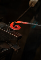 The blacksmith twists the spiral with the help of an anvil, heating the iron blank to red. Work in the forge