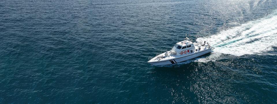 Aerial drone ultra wide photo of Hellenic Coast guard powerboat cruising in high speed near port of Piraeus, Attica, Greece