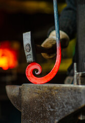 The blacksmith twists the spiral with a sledgehammer, placing a red-hot iron blank on the anvil. Work in the forge