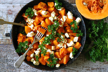 Pieces of pumpkin baked with feta cheese in a pan. Warm pumpkin salad. Autumn dishes ideas.