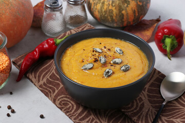 Vegetarian autumn creamy pumpkin soup with red lentils on dark plate. Closeup. Horizontal format.