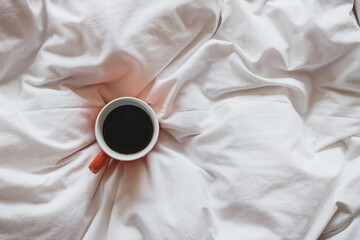 Cup of coffee on bed, top view
