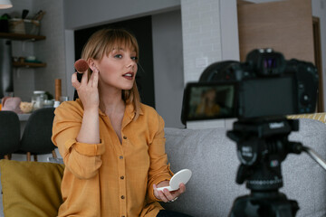 Female vlogger recording makeup tutorial for her channel. Young beautiful woman recording make up...