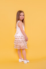Shot of a  little  smiling girl with long blonde hair  against yellow background with copy space in studio