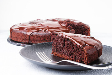 Chocolate cake in a black plate with a fork on a white background with copy space horizontal