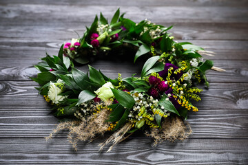 Beautiful wreath made of flowers and leaves on wooden table