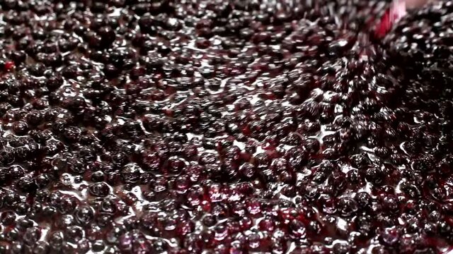 Stir with a spoonful of blueberry jam. Making jam from wild blueberries, jam