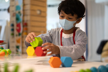 Asian boy wear face masks to prevent the Coronavirus 2019 and play toy in schools.