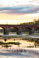 Late evening sunset view of old historic brick bridge over river Venta.