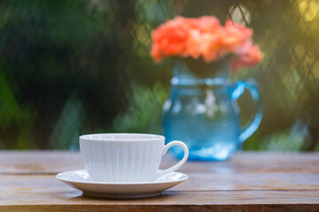 A beautiful set of white coffee mugs on a wooden table in a natural setting in the morning.
