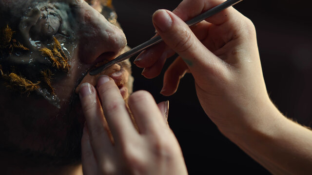 Makeup artist doing man makeup for halloween costume as zombie