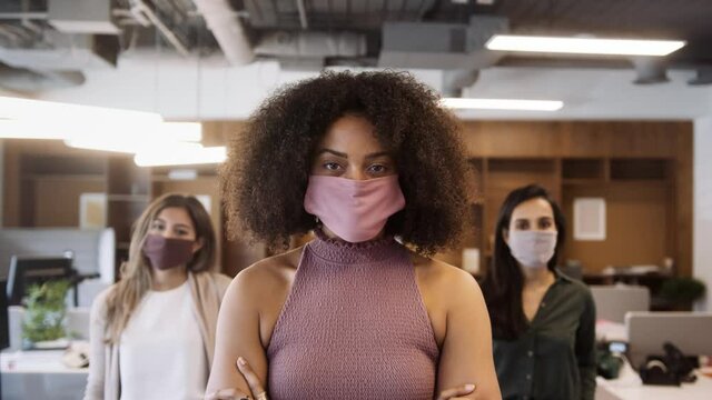 Portrait of female business team wearing face masks in open plan office during covid-19 pandemic - shot in slow motion