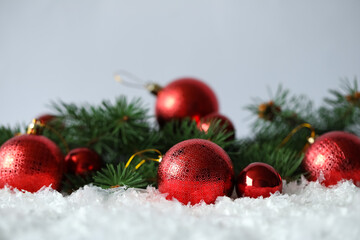 Naklejka na ściany i meble Beautiful Christmas balls and fir branches on snow against grey background. Space for text