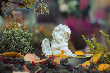 Remembrance concept: White angel on a grave, flowers