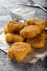 Chicken Nuggets on parchment paper with sour cream sauce, fork and knife.
