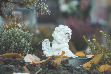 Remembrance concept: White angel on a grave, flowers