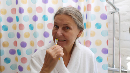 Portrait of senior woman brushing her teeth in bathroom at home