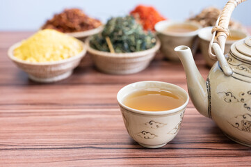 Selective focus hot chinese kettle and small cup with out of focus dry herbal cup.Coffee and tea time concept.