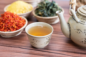 Selective focus hot chinese kettle and small cup with out of focus dry herbal cup.Coffee and tea...