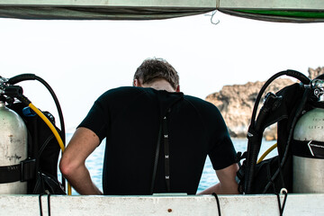 A scuba diver in a wetsuit between two oxygen tanks, Ngwesaung, Myanmar