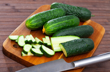 Many ripe juicy cucumbers on wooden surface closeup