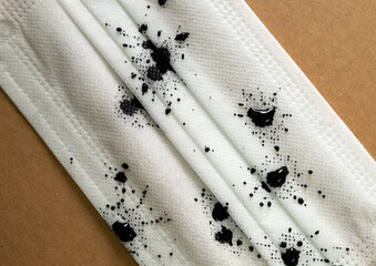 White surgical mask with black blotches