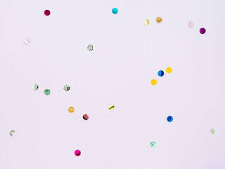 Multi-colored shiny round confetti on a pink background, top view, copy space, flat lay