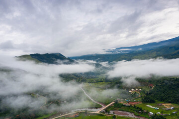 Aerial view over valley surrounded by mountains and covered with dense ground fog and mist High peaks wonderful morning sunrise natural Landscape. Sapan village, nan province, Thailand.