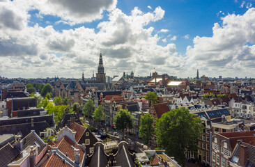Naklejka na ściany i meble Beautiful Amsterdam Cityscape from Aerial rooftop perspective above Canals and Church Tower View with Blue Sky and big clouds