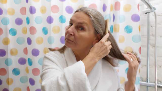 Portrait of senior woman brushing hair in bathroom