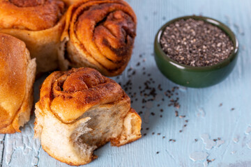 Freshly baked wheat buns with poppy seeds on blue wooden background.