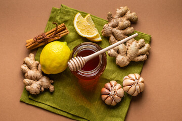 Honey glass pot, ginger, garlic, lemon, cinnamon top view to boost immune system. Natural food ingredients for immunity stimulation and viruses protection. Healthy food against seasonal flu and cold.