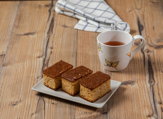 Three pieces of cake and a cup of tea over a wooden table