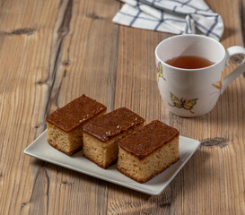 Three pieces of cake and a cup of tea over a wooden table