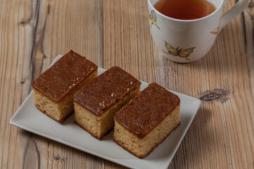 Three pieces of cake and a cup of tea over a wooden table