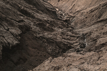 Dark Aged Shabby Landslip Surface Divided By Huge Cracks And Layers. Coarse Brown Mud And Clay Or Rock Texture Of Mountains, Background And Space For Text On Theme Geology And Mountaineering Concept. 