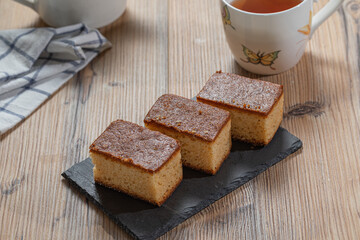 Three pieces of cake and a cup of tea over a wooden table