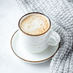 White mug with coffee and wool scarf on stone background. Winter composition in scandinavian style. Copy space for text