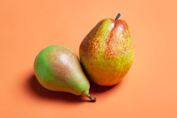 Two pears. Fresh ripe organic pears on an orange background. Vegetarian, vegan healthy food. Diet organic product. Selective soft focus.